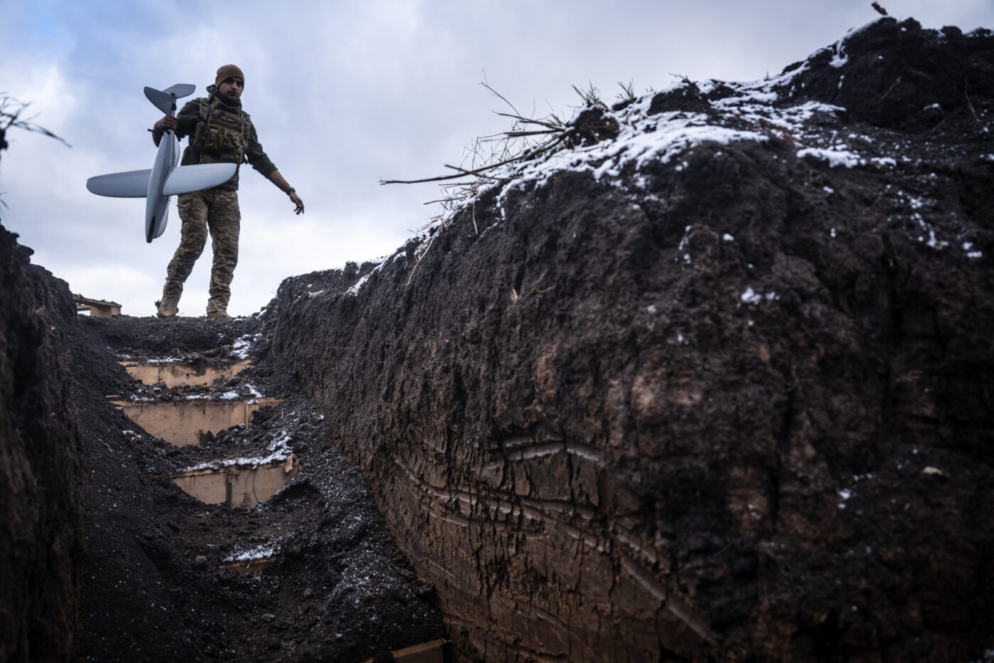 Украинский военнослужащий несет разведывательный беспилотник во время перемещения по окопам в районе Покровска